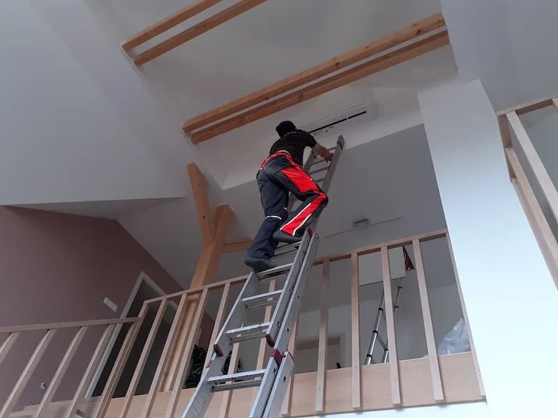 Technik Klimahome montuje klimatizaci na žebříku v podkroví