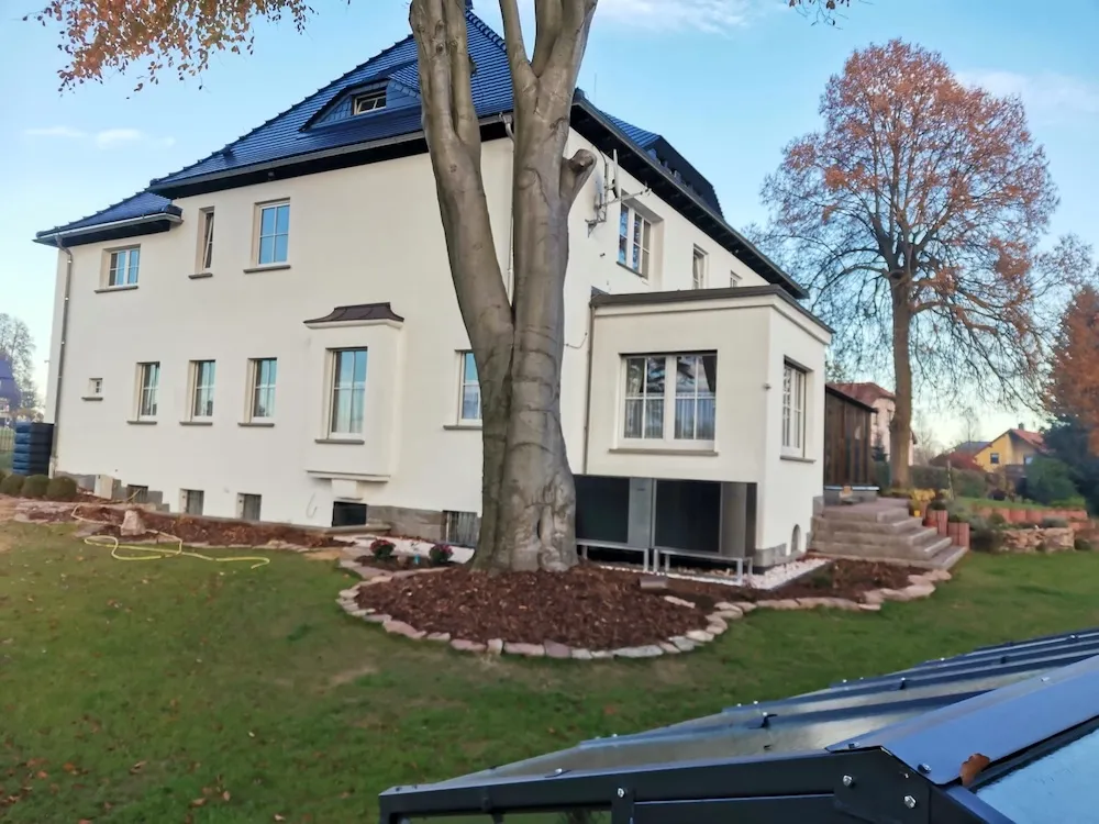 Tepelné čerpadlo namontované u fasády rodinného domu v zimě